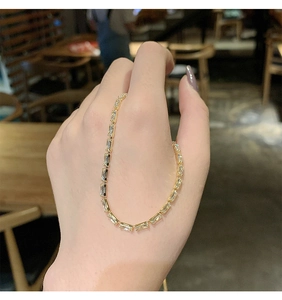 Detail of a minimalist gold chain bracelet featuring rectangular clear zircon stones