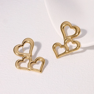 Minimalist gold hollow triple heart stainless steel earrings on white textured surface