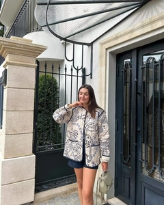 Street style view of a quilted floral jacket with blue paisley patterns and dark trim