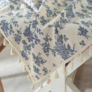 Blue floral cotton linen tablecloth with fringe edges on white wooden table
