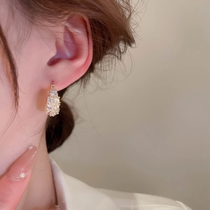 Close-up of gold-plated drop earrings with sparkling pavé zircons on a model