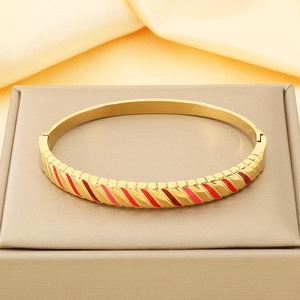 Detailed close-up of 18K gold-plated hinged bangle with red enamel slanted patterns