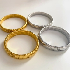 Detailed view of elastic textured tube bracelets in polished gold and silver finishes