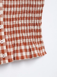 Detail of brown and white checkered fabric featuring a smocked texture and white buttons