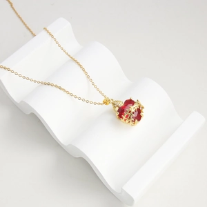 Gold plated cross necklace with red heart zircon and thorn vine wrap design on wavy stand