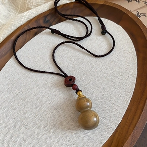 Detailed macro of wooden gourd pendant on wax cord with traditional Chinese weaving style