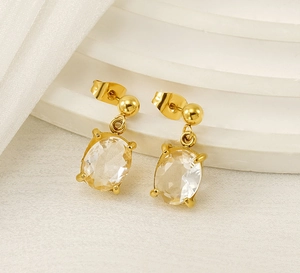 Detail of oval cubic zirconia drop earrings in gold plating on a white display stand