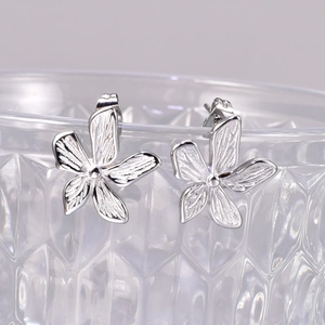 Macro shot of silver floral earrings with 18k gold plating on textured glass rim