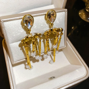 Detailed macro of gold tassel earrings with pearls and crystals in a beige jewelry box
