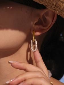 Gros plan de boucles d'oreilles ovales dorées avec micro-pavage de zircons sur mannequin