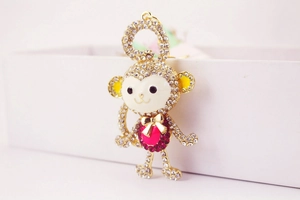 Macro detail of crystal monkey keychain featuring a pink heart gem and golden bow