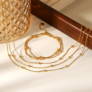 Close-up of golden multi-layer bead chain necklace and matching bracelet set