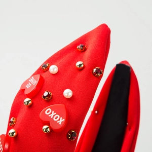 Détail d'un serre-tête rouge avec des cœurs BE MINE, des perles et des strass brillants