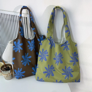 Detailed close-up showing blue floral patterns on brown and green canvas tote bags