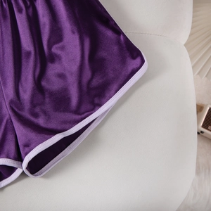 Close-up of purple satin sports shorts showing white piping and elastic waistband texture
