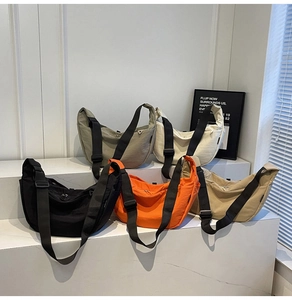 Collection of nylon dumpling bags in five colors displayed on white stairs for daily commute