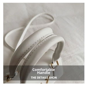 Detailed close-up of the white leather handle with reinforced stitching and gold metal hardware
