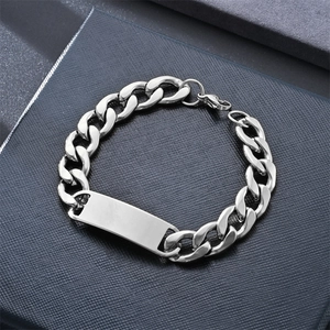 Macro detail of silver Cuban chain bracelet with blank metal ID plate on jewelry box