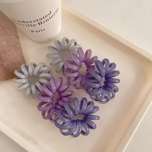 Detailed shot of six elastic jelly color spiral hair ties in gray and purple on a white tray