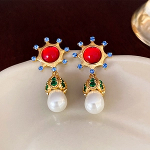 Macro detail of vintage gold earrings with colorful rhinestones and teardrop pearl charms