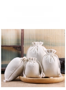 Detail view of four sizes of thick cotton canvas drawstring pouches on a wooden tray