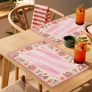 Pink Christmas placemat with gingerbread house and teddy bear on a wooden dining table