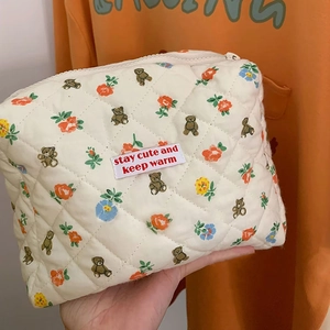 Close-up of quilted cotton makeup bag with bear and floral pattern and logo tag