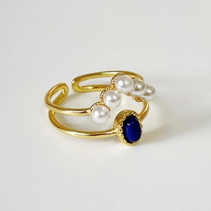 Minimalist double-layered gold ring featuring graduated pearls and a blue gemstone centerpiece