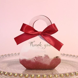 Detail of pink and red handbag style wedding candy box with silk ribbon and gold foil