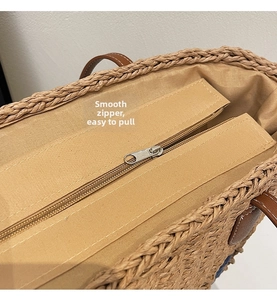 Detail view of smooth zipper closure and woven texture on a large khaki straw tote bag