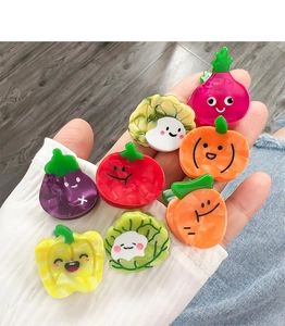Close-up of small acetate hair clips in cute vegetable shapes held in palm
