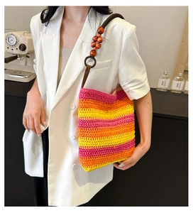 Close-up of woven straw bucket bag with rainbow gradient stripes and wood bead strap