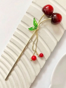 Close-up of golden metal hair stick featuring dark red cherries and green leaf details