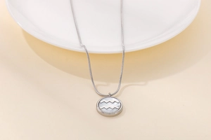 Macro detail of silver Aquarius zodiac necklace with white shell inlay and sleek snake chain