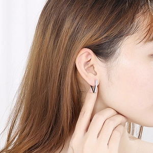 Close-up of a model wearing a polished silver geometric V-shaped stainless steel stud earring