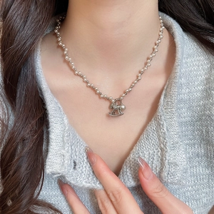 Close-up of pearl bead necklace with a sparkling rocking horse pendant on a sweater