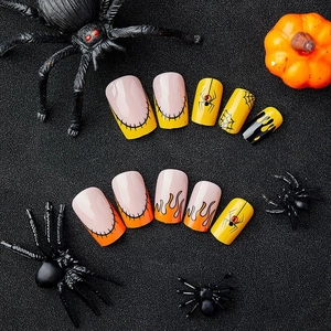 Halloween press-on nails with yellow and black spider, flame patterns and rhinestone accents