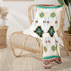 Bohemian geometric flannel blanket with tribal patterns draped over a stylish rattan chair