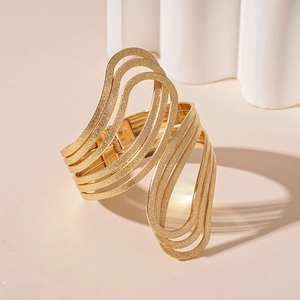Detail of gold multi-layered wavy open cuff bracelet with matte textured finish