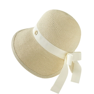 Elegant wide brim straw sun hat with white ribbon bow and gold logo detail
