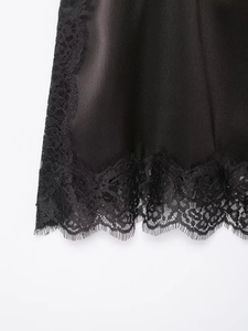 Gros plan détaillé du tissu en satin noir lisse et de la dentelle délicate sur l'ourlet