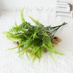 Artificial Boston fern leaves placed on a wooden stand over a white textured rug