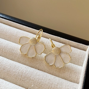 Macro view of gold flower earrings with pearly white petals in a textured velvet box