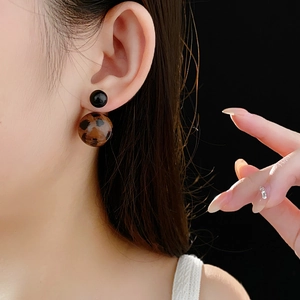 Detail view of double-sided leopard print ball earrings with black stud on a model