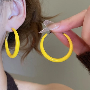 Vue détaillée de créoles géométriques jaunes en forme de C portées par un mannequin chic