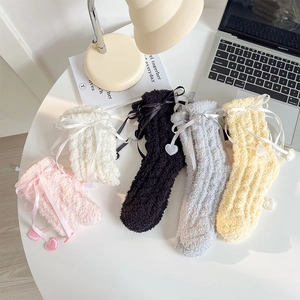 Gros plan de cinq chaussettes en molleton corail avec nœuds en ruban et pendentifs cœur