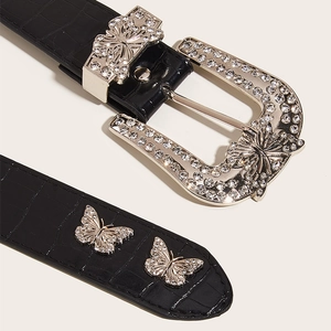 Detailed macro shot of black crocodile texture belt with butterfly rhinestone buckle
