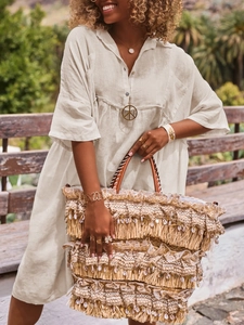 Close-up of bohemian fringed woven handbag paired with linen shirt dress and jewelry