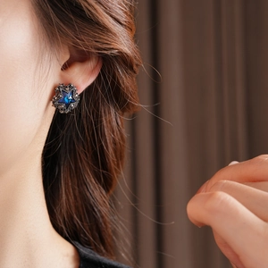 Nahaufnahme eines blauen sternförmigen Ohrrings mit Kristallen, Vintage-Stil am Ohr