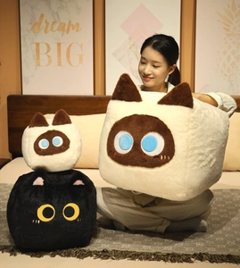 Detailed view of plush square cat pillows in different sizes shown in a cozy home setting